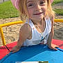 blue_surface, casual_clothing, child, daylight, girl, grass, happy, keys, map, necklace, outdoor, park, pink_hat, playground, playing, smiling, sunny, white_tank_top, yellow_rail, young