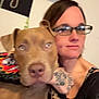 Dyno is registered to the contest to win money with this photo: animal, blurry, brown_dog, candid, casual, close_up, dog, eyelashes, face, flame_pattern, friendship, glasses, human, indoor, pet, portrait, selfie, tattoo, tattooed_hand, woman