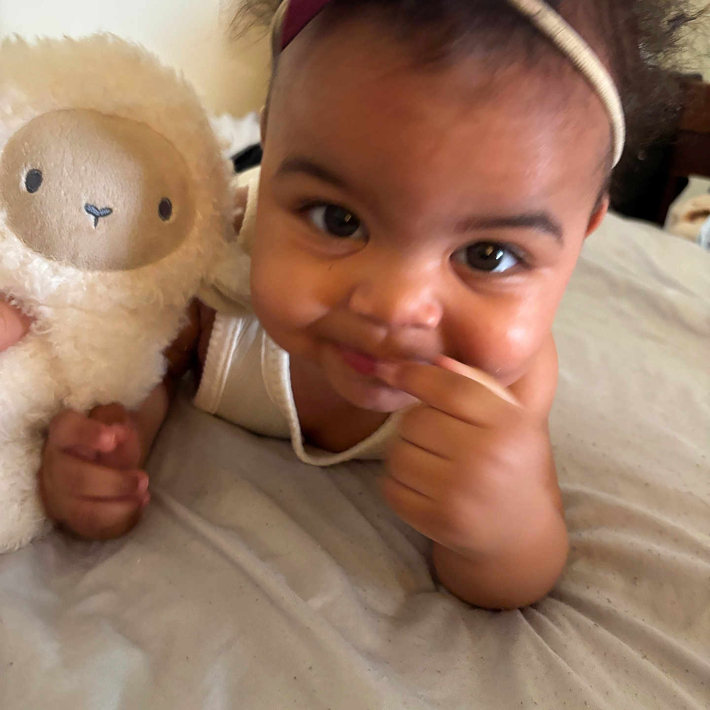 Elora joined the competition — help win amazing prizes! toddler, child, baby, headband, stuffed_animal, toy, bed, blanket, smiling, face, hand, curly_hair, indoors, cute, person, portrait, playful, skin, expression, closeup