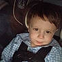 child, car_seat, seatbelt, checkered_shirt, young_boy, indoors, portrait, serious_expression, straps, hair, face, clothing, safety, car_interior, baby, person, young_child, seat, travel, transportation