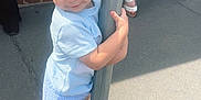 Pave is registered to the contest to win money with this photo: toddler, child, blond_hair, shorts, blue_shirt, sandals, metal_pole, sidewalk, curb, shadow, people, brick_wall, summer, outdoor, cute, holding, standing, sunlight, casual, urban