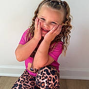 Parklynn joined the competition — help win amazing prizes! child, girl, smiling, curly_hair, pink_shirt, leopard_print_pants, kneeling, indoor, wooden_floor, white_wall, happy, portrait, casual_clothing, cute, young, playful, hands_on_face, fashion, childhood, person