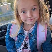 Paisley joined the competition — help win amazing prizes! child, girl, blue_eyes, denim_jacket, black_bow, car_seat, seatbelt, backpack, curly_hair, skirt, bows, casual_clothing, portrait, smile, indoors, daylight, seat, cute, fashion, person
