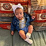 Ghjulia participe au concours pour gagner de l'argent avec cette photo : baby, child, headwrap, denim_jacket, socks, couch, cushions, patterned_fabric, indoor, seated, curious_expression, small_child, textile, comfortable, casual_clothing, infant, portrait, home_interior, soft_lighting, relaxed
