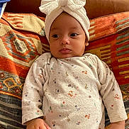 Ghjulia participe au concours pour gagner de l'argent avec cette photo : baby, infant, headband, bow, onesie, patterned_clothing, blanket, colorful, indoor, cute, child, portrait, relaxed, young, person, small_hands, face, expression, seated, soft_lighting