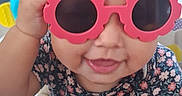 Alani joined the competition — help win amazing prizes! baby, child, sunglasses, pink, flower_shape, smiling, playing, activity_center, toy, hand, face, cute, indoor, person, clothing, short_sleeve, hair, expression, fun, happy