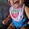 baby, child, smiling, bib, pink_hat, drool, blue_clothing, sitting, couch, happy, cute, indoor, face, person, infant, portrait, clothing, headwear, toddler, fun