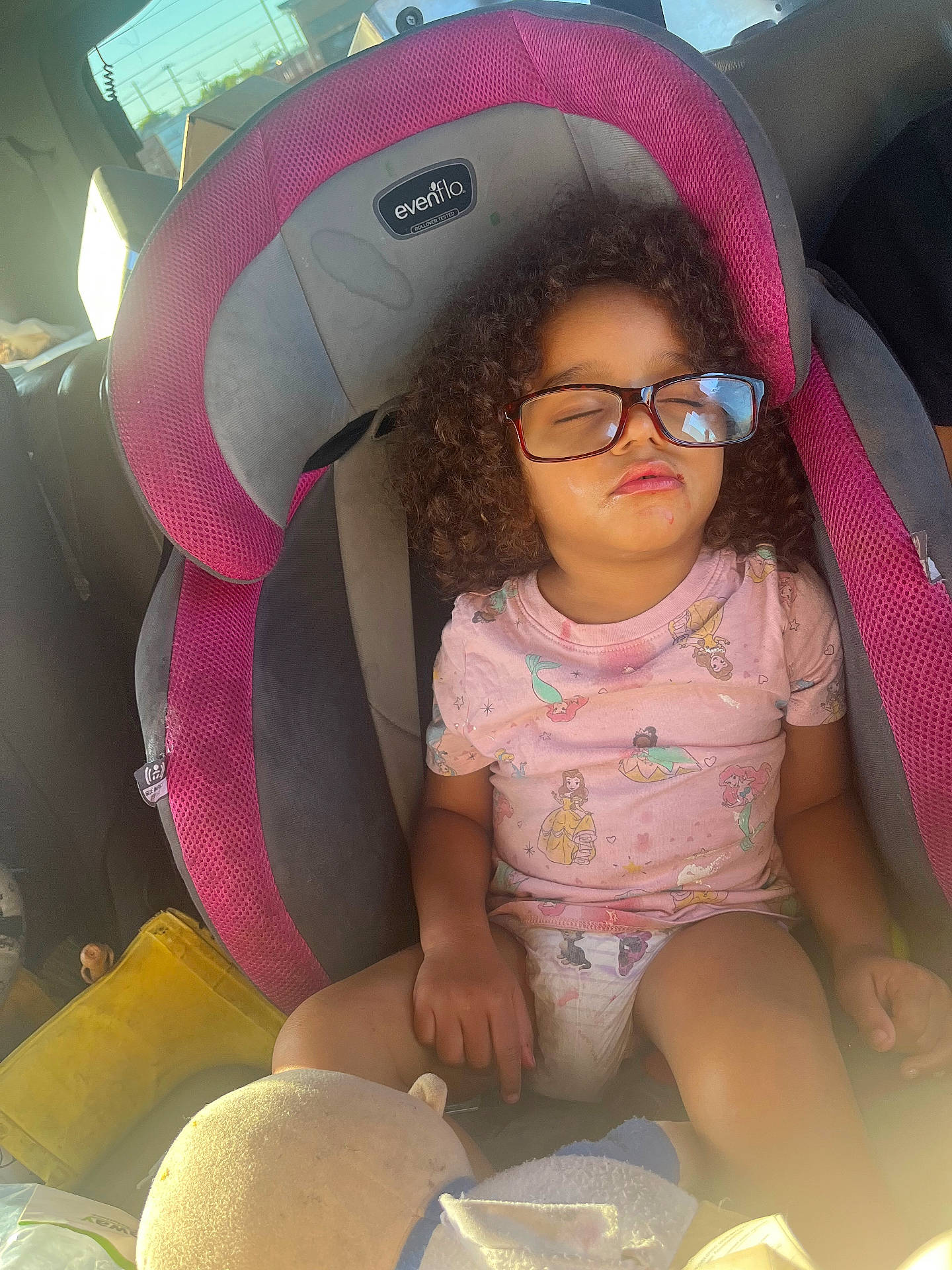 Aariyanah is registered to the contest to win money with this photo: car_interior, car_seat, cartoon_characters, casual, child, clothing, curly_hair, diaper, face, glasses, indoors, person, pink_shirt, relaxing, seatbelt, sleeping, sunlight, toy, transportation, young_child