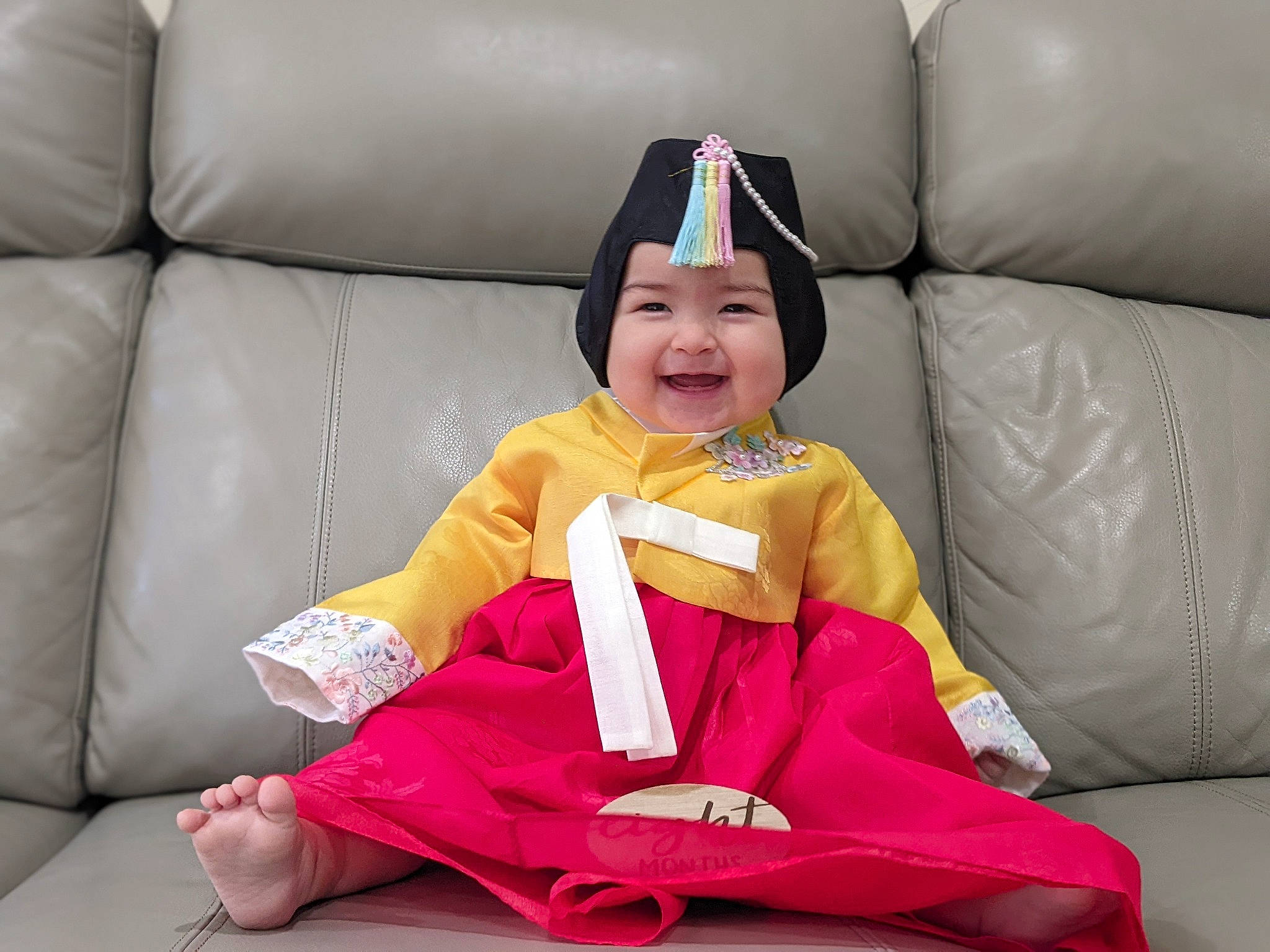Isa is registered to the contest to win money with this photo: baby, baby_toddler_clothing, child, comfort, costume_hat, couch, eye, happy, head, headwear, joy, lap, leg, magenta, person, pink, purple, sitting, smile, textile