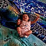 Caitlin participe au concours pour gagner de l'argent avec cette photo : baby, infant, child, romper, blanket, sea_turtle, map, blue, green, pattern, lying_down, arms_up, curious, relaxed, indoors, soft_lighting, colorful, fabric, cute, portrait