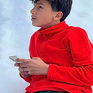 James is registered to the contest to win money with this photo: child, boy, red_fleece, smartphone, casual_clothing, short_hair, side_profile, sitting, curious_expression, indoor, technology, young_person, portrait, hands, looking_away, light_background, modern, relaxed, youth, focused