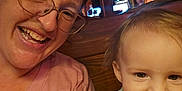 Colton is registered to the contest to win money with this photo: baby, background, candid, casual_clothing, child, closeup, face, family, glasses, happy, indoor, joy, light, person, portrait, smiling, toddler, tshirt, woman, wooden_bench