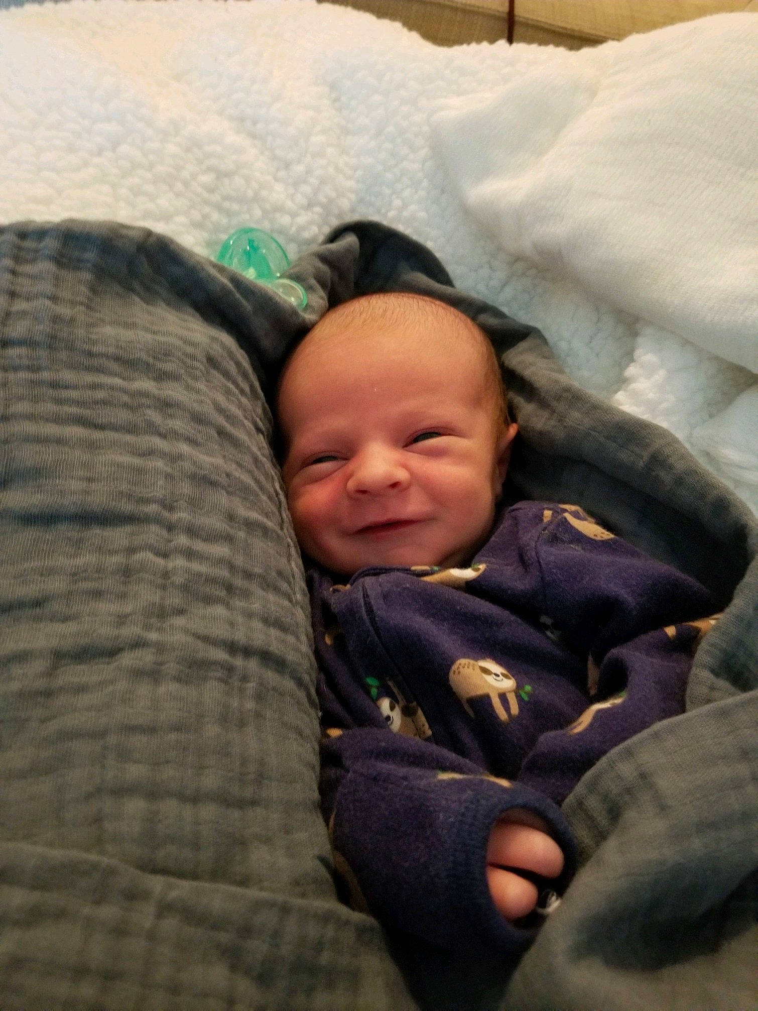 Justin is registered to the contest to win money with this photo: baby, baby_toddler_clothing, bedtime, cheek, child, comfort, facial_expression, grass, happy, head, linens, mammal, nap, person, room, sitting, smile, toddler, tree, winter