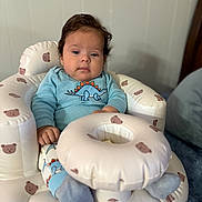 Gael is registered to the contest to win money with this photo: baby, child, infant, dinosaur_clothing, blue_clothing, inflatable_chair, bear_pattern, socks, indoor, soft_toys, cute, face, person, seated, plush, young_child, comfort, relaxed, portrait, home