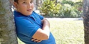 Sidi Mikhail a rejoint le concours — aidez-le/la à gagner de superbes lots ! boy, child, tree, park, outdoor, grass, sunlight, greenery, palm_tree, casual_clothing, shorts, blue_shirt, nature, daylight, person, standing, arms_crossed, leisure, summer, portrait