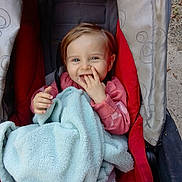 Bella participe au concours pour gagner de l'argent avec cette photo : toddler, child, stroller, blanket, smiling, baby, outdoor, clothing, face, person, hand, red, gray, fabric, seat, comfort, happy, cute, young, striped_pants