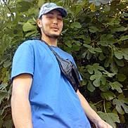 Samy participe au concours pour gagner de l'argent avec cette photo : background, blue_tshirt, candid, cap, casual, daylight, fanny_pack, foliage, greenery, leaves, male, nature, outdoor, person, plants, portrait, relaxed, standing, trees, young_adult