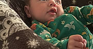 Bentley joined the competition — help win amazing prizes! animal_pattern, baby, blanket, child, close_up, couch, cozy, curious, eyes, face, family_photo, fist, green_outfit, hand, indoors, infant, lying_down, pajamas, portrait, soft_lighting