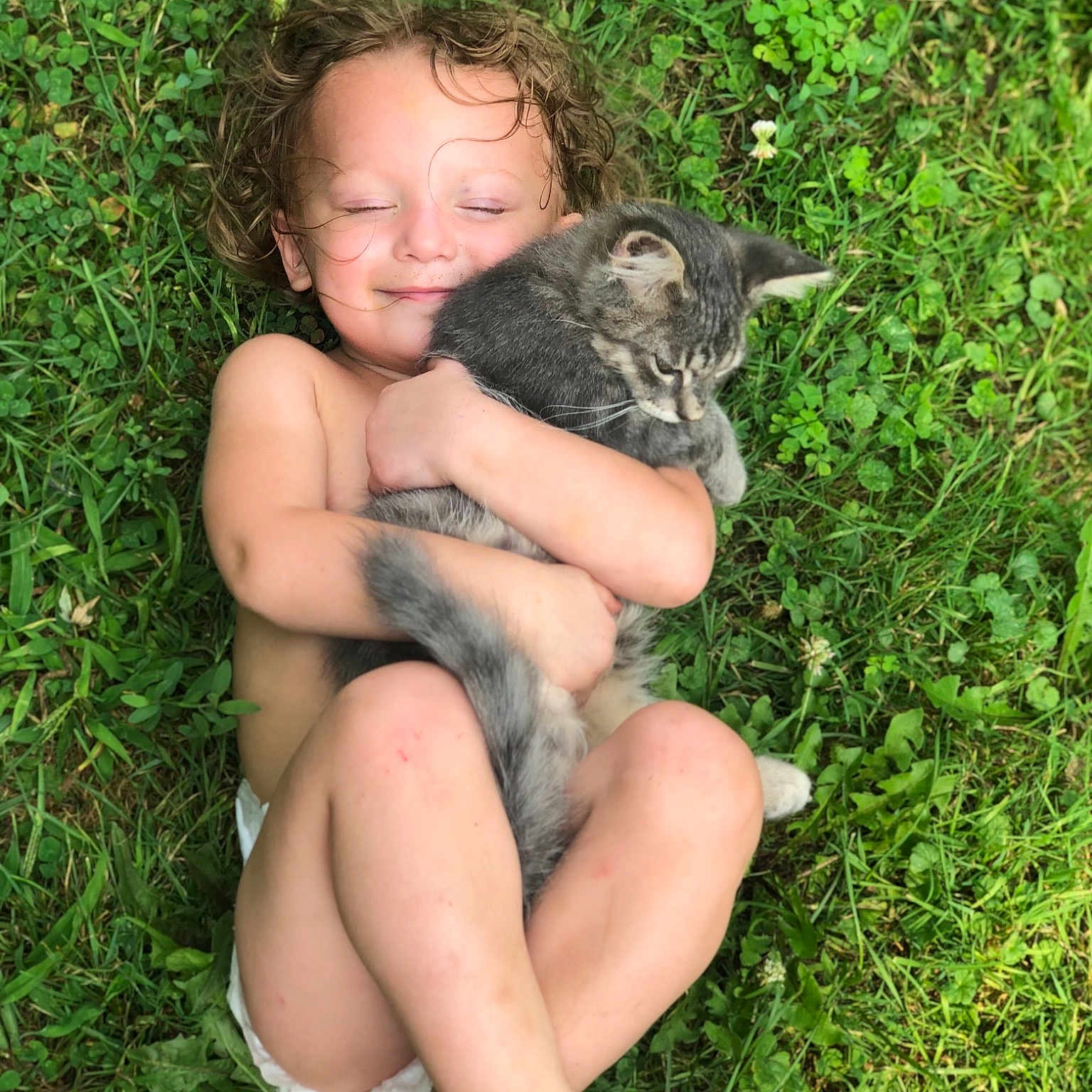 Veronica is registered to the contest to win money with this photo: barefoot, fawn, finger, foot, grass, groundcover, happy, human_leg, lap, mammal, organism, people_in_nature, plant, primate, skin, terrestrial_animal, thigh, thumb, toddler, vertebrate