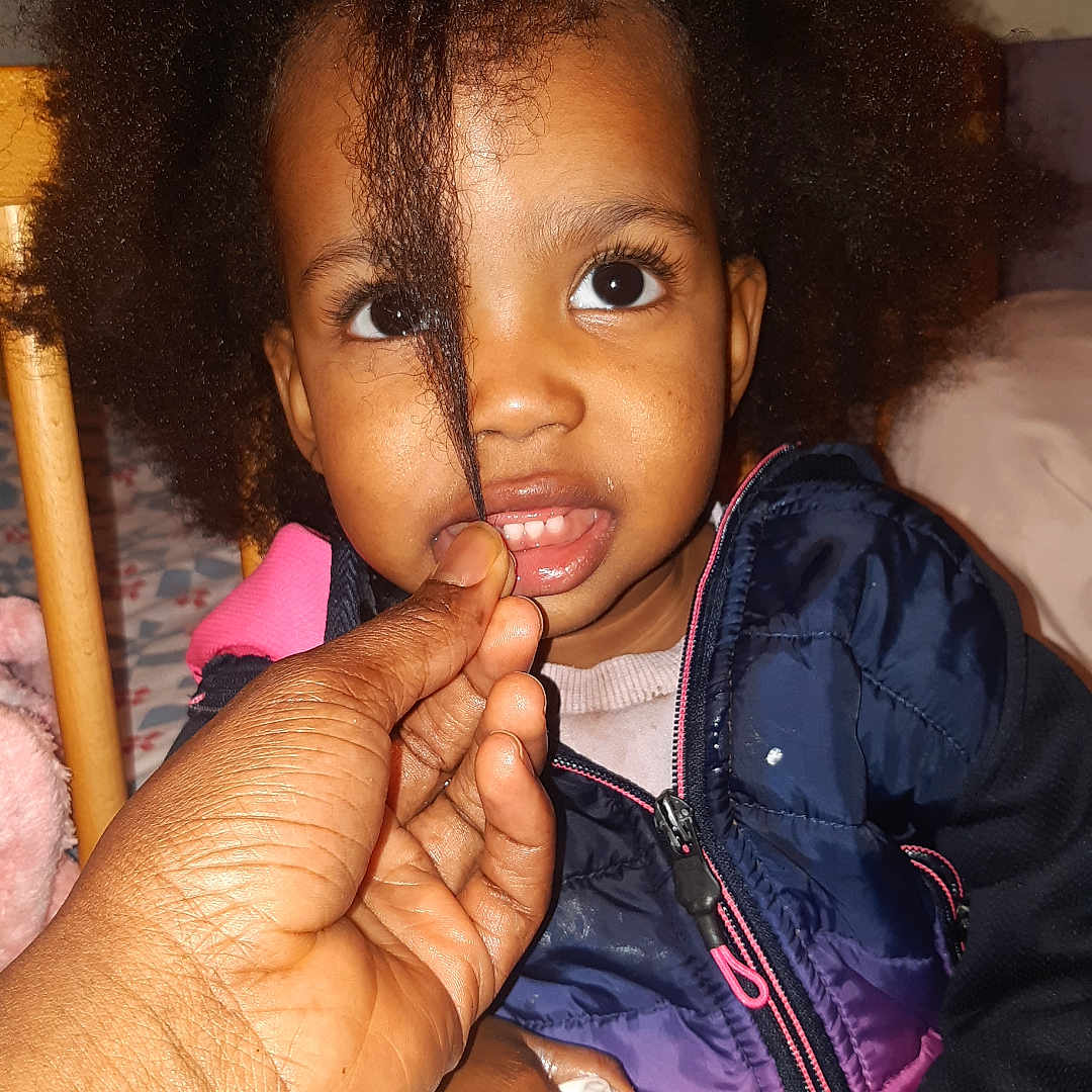 Kailane a rejoint le concours — aidez-le/la à gagner de superbes lots ! afro_hair, child, closeup, clothing, curious, expression, eyes, face, fingers, hair, hand, indoor, jacket, lotion_bottle, person, playing, portrait, seated, skin, toddler