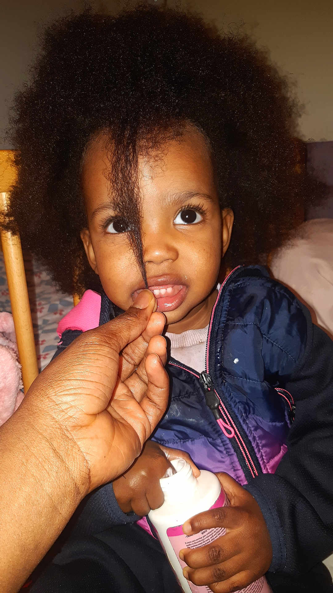 Kailane a rejoint le concours — aidez-le/la à gagner de superbes lots ! child, toddler, afro_hair, hand, lotion_bottle, curious, indoor, person, clothing, jacket, face, eyes, hair, skin, fingers, playing, expression, closeup, portrait, seated