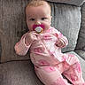 baby, infant, child, sitting, couch, cushion, pacifier, pink_outfit, elephant_pattern, onesie, portrait, indoor, cozy, gray_background, short_hair, looking_at_camera, calm, cute, soft_lighting, home