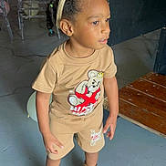 Andre is registered to the contest to win money with this photo: child, bunny_ears, tan_clothing, boots, indoor, floor, curious, standing, person, shorts, tshirt, brown_shoes, hair, headband, wooden_ramp, concrete_floor, casual, furniture, playful, portrait