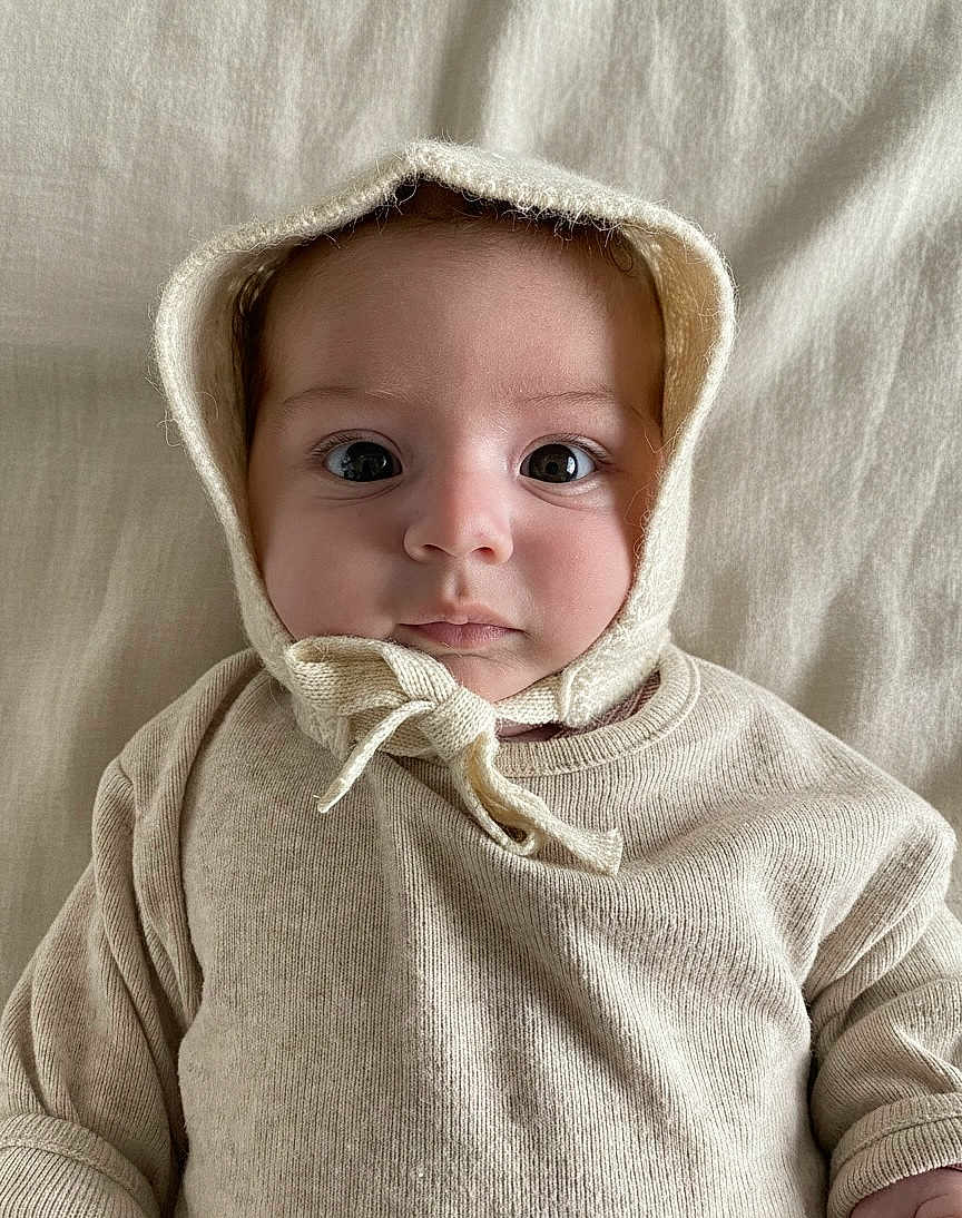 Blanche a rejoint le concours — aidez-le/la à gagner de superbes lots ! baby, infant, face, eyes, knit_bonnet, cream_color, sweater, clothing, portrait, soft_texture, blanket, lying_down, cute, child, newborn, closeup, indoors, calm, adorable, young
