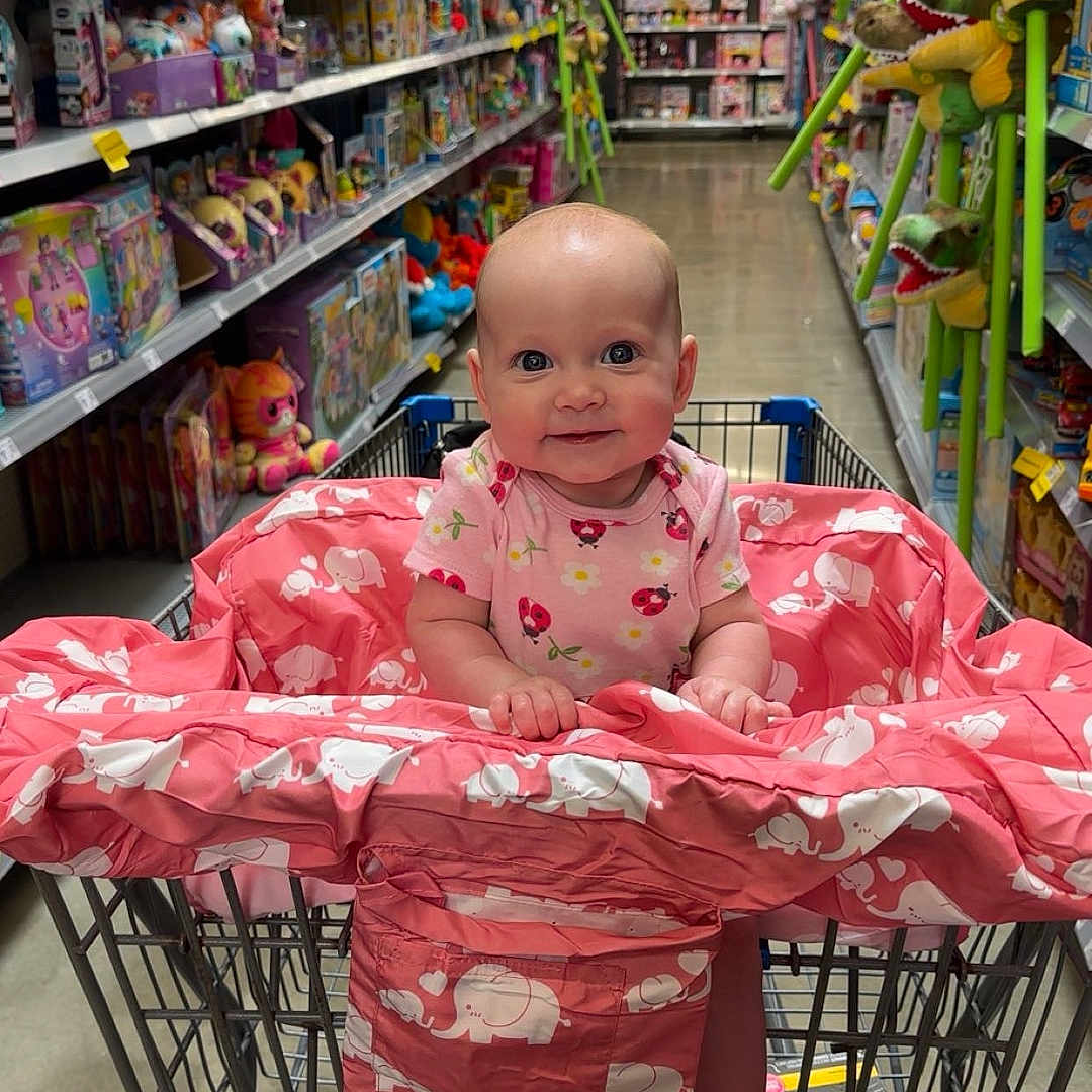 Eowyn joined the competition — help win amazing prizes! aisle, baby, child, clothing, cute, elephant_pattern, floor, happy, indoor, infant, person, pink, retail, shopping, shopping_cart, smiling, socks, store_shelves, toy_store, toys