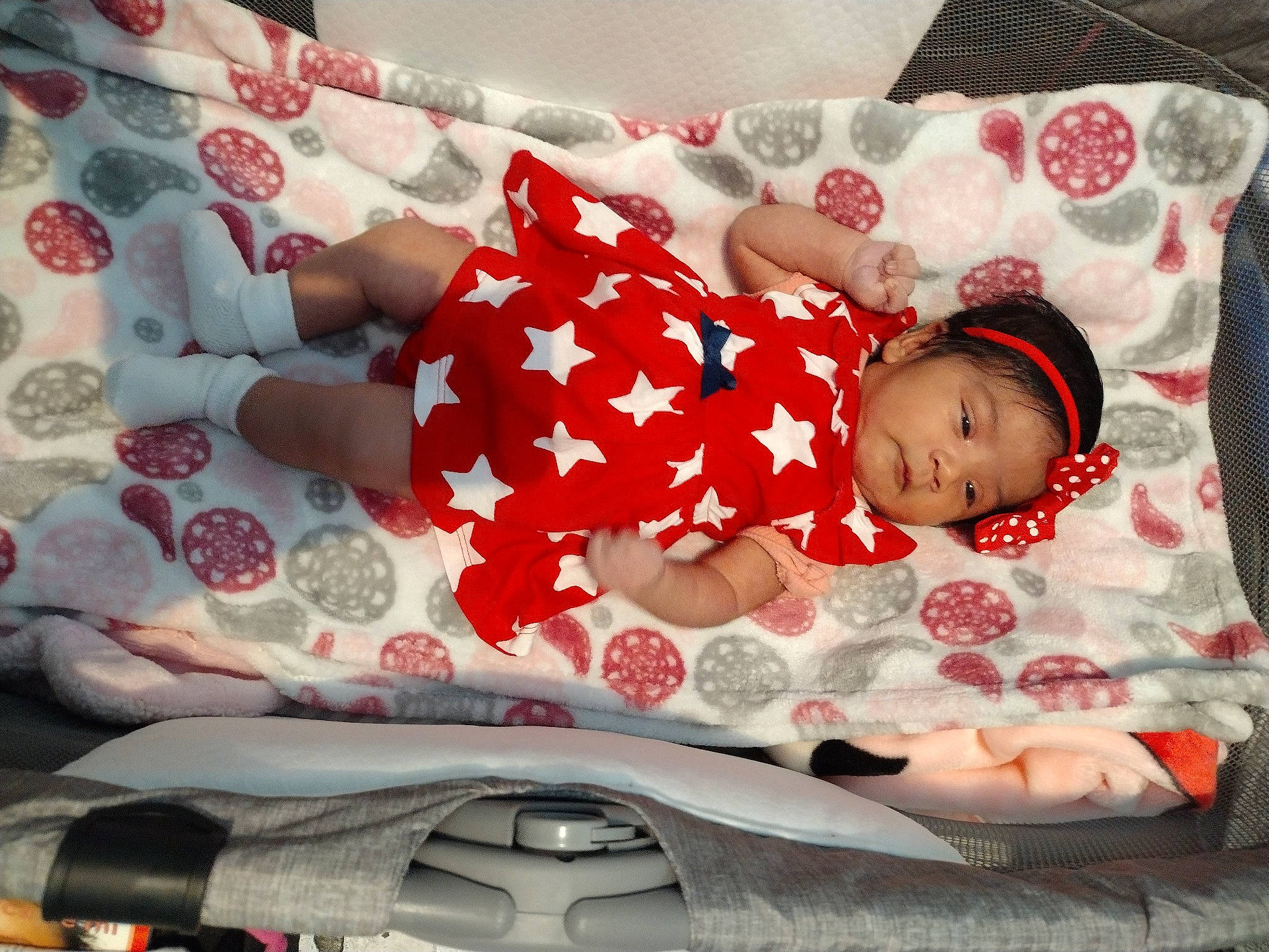 Aliyah is registered to the contest to win money with this photo: arm, baby, baby_products, baby_toddler_clothing, carmine, child, comfort, headwear, human_leg, lap, linens, pattern, person, pink, product, red, sitting, sleeve, sock, textile