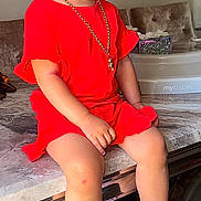 Monroe Blu is registered to the contest to win money with this photo: toddler, child, girl, red_clothing, pigtails, red_bows, gold_chain, earrings, pink_crocs, marble_table, indoor, living_room, television, furniture, flooring, cute, sitting, portrait, person, young_child