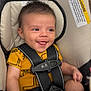 baby, smiling, car_seat, safety_harness, yellow_clothing, pacifier, infant, cute, child, seat_belt, indoor, happy, young_child, plush_padding, portrait, seated, secure, infant_clothing, human, closeup