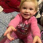 Harlenn joined the competition — help win amazing prizes! bed, blanket, blond_hair, child, cozy, cute, face, foot, happy, home, indoor, person, pink_pajamas, plush_toy, reaching, sitting, sleepwear, smiling, toddler, young_child