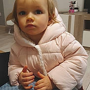Mya participe au concours pour gagner de l'argent avec cette photo : toddler, child, pigtails, pink_jacket, puffer_jacket, indoor, blanket, hands, curious, face, person, home, floor, furniture, table, shoes, warm_clothing, portrait, cute, expression