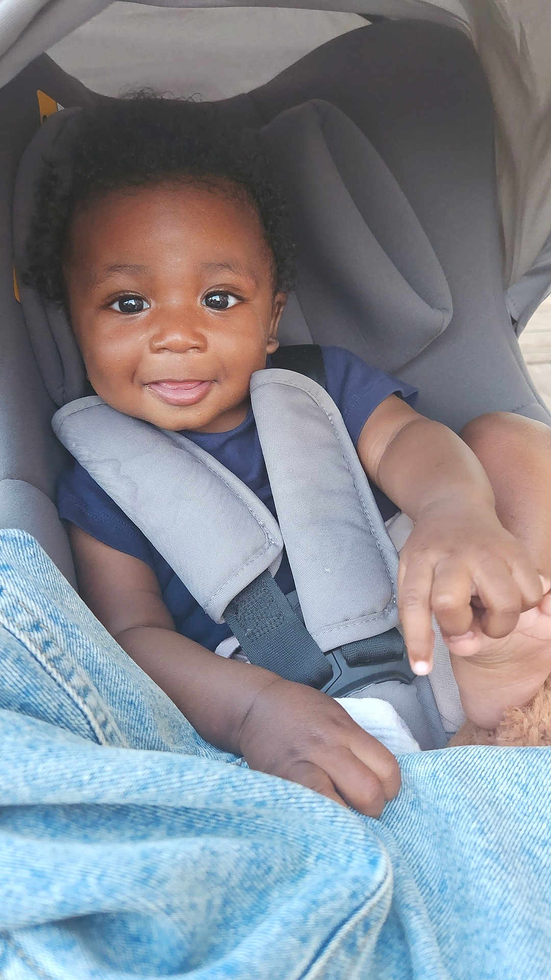 Zayonn a rejoint le concours — aidez-le/la à gagner de superbes lots ! baby, car_seat, casual, child, closeup, clothing, cute, denim, face, hands, happy, indoors, infant, person, portrait, seatbelt, secure, sitting, smiling, young_child