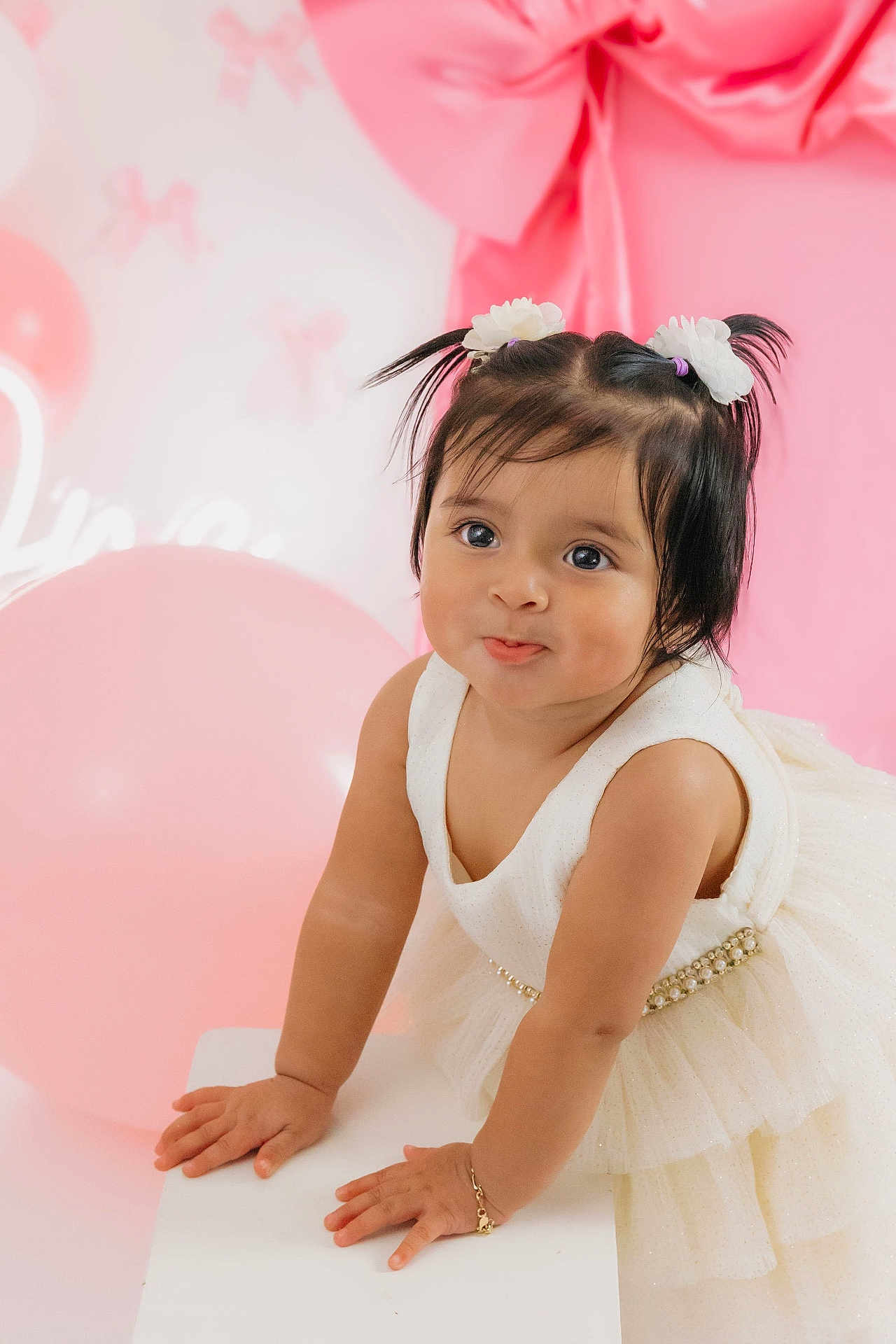 Nashly joined the competition — help win amazing prizes! toddler, child, baby, dress, white_dress, cute, portrait, pink_background, balloons, party, celebration, hair_ties, flower_accessories, smile, happy, indoor, cute_face, bracelet, hands, posing