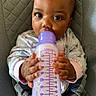 baby, infant, child, bottle, feeding, milk, sitting, chair, portrait, close_up, face, eyes, hands, onesie, floral_clothing, purple, indoor, lounge_chair, cute, photography