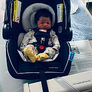 Ethan joined the competition — help win amazing prizes! newborn, baby, car_seat, hospital_bed, medical_equipment, infant, sleeping, onesie, yellow_socks, blanket, hospital_room, paper, strap, black_car_seat, white_bed, infant_carrier, resting, child, person, indoor