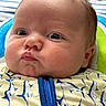 Sutton is registered to the contest to win money with this photo: baby, close_up, face, infant, chubby_cheeks, curious_expression, blue_zipper, fish_pattern, clothing, cushion, striped_background, indoor, portrait, child, cute, young, person, skin, head, eyes