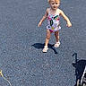 toddler, child, playground, swimsuit, blue_surface, outdoor, sunny, stroller, walking, tree, grass, sidewalk, car, shadow, summer, person, young_child, happy, playing, park
