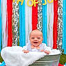 baby, tub, blanket, bow_tie, grass, daisy, flower, outdoor, celebration, decoration, banner, streamers, smile, happy, person, festive, summer, holiday, cute, portrait
