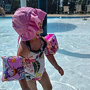 River Grace is registered to the contest to win money with this photo: child, pool, water, floaties, pink_hat, swimsuit, outdoor, summer, sunlight, recreation, swimming, playing, water_toys, fun, daytime, vacation, kid, safety, leisure, holiday