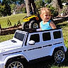 River Grace joined the competition — help win amazing prizes! blonde_hair, blue_sky, child, daytime, fun, grass, greenery, kid, nature, outdoor, park, play, recreation, small_car, smiling, sunny, tank_top, toy_car, trees, vehicle