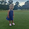 River Grace is registered to the contest to win money with this photo: child, girl, blue_dress, pink_shoes, grass, outdoor, nature, trees, sky, clouds, pond, field, standing, casual, daylight, young_child, park, greenery, summer, portrait