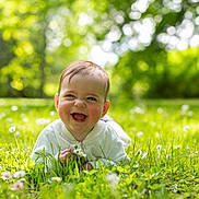 Gabin participe au concours pour gagner de l'argent avec cette photo : baby, grass, flower, greenery, outdoor, nature, infant, happy, smiling, child, sunlight, spring, summer, cute, portrait, face, fresh, playful, lying_down, daylight