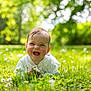 baby, grass, flower, greenery, outdoor, nature, infant, happy, smiling, child, sunlight, spring, summer, cute, portrait, face, fresh, playful, lying_down, daylight