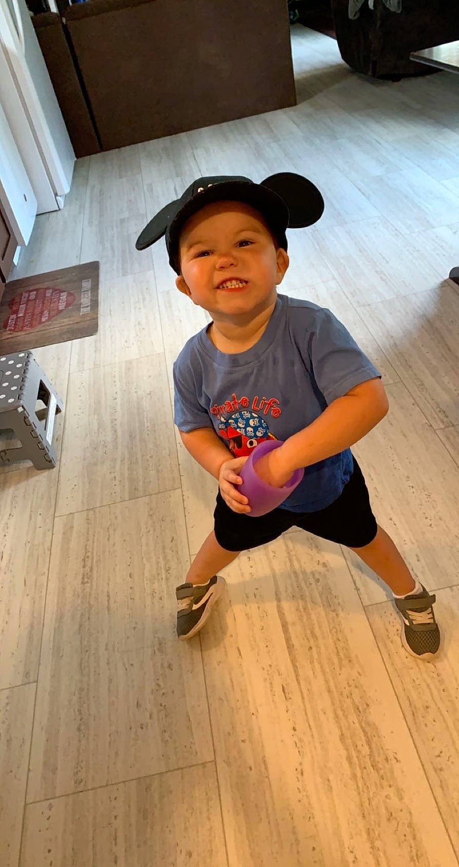 Vincent is registered to the contest to win money with this photo: child, eye, face, floor, flooring, fun, happy, hardwood, headwear, human_leg, knee, laminate_flooring, leisure, person, sleeve, t_shirt, thigh, toddler, varnish, wood