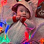 baby, blanket, christmas_book, christmas_lights, colorful_lights, cozy, cute, expression, face, festive, holiday, hood, indoor, infant, lying_down, onesie, red_cuffs, reindeer_ears, soft_texture, warm_clothing
