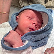 Maël a rejoint le concours — aidez-le/la à gagner de superbes lots ! newborn, baby, sleeping, hooded_towel, blue, soft_texture, hand, bracelet, skin, closeup, peaceful, infant, wrapped, cute, child, resting, cozy, portrait, indoors, human