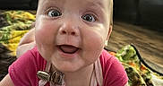 Paisley is registered to the contest to win money with this photo: baby, smiling, crawling, blanket, living_room, happy, child, face, cute, indoors, person, infant, clothing, expression, floor, skin, head, eyes, mouth, joy